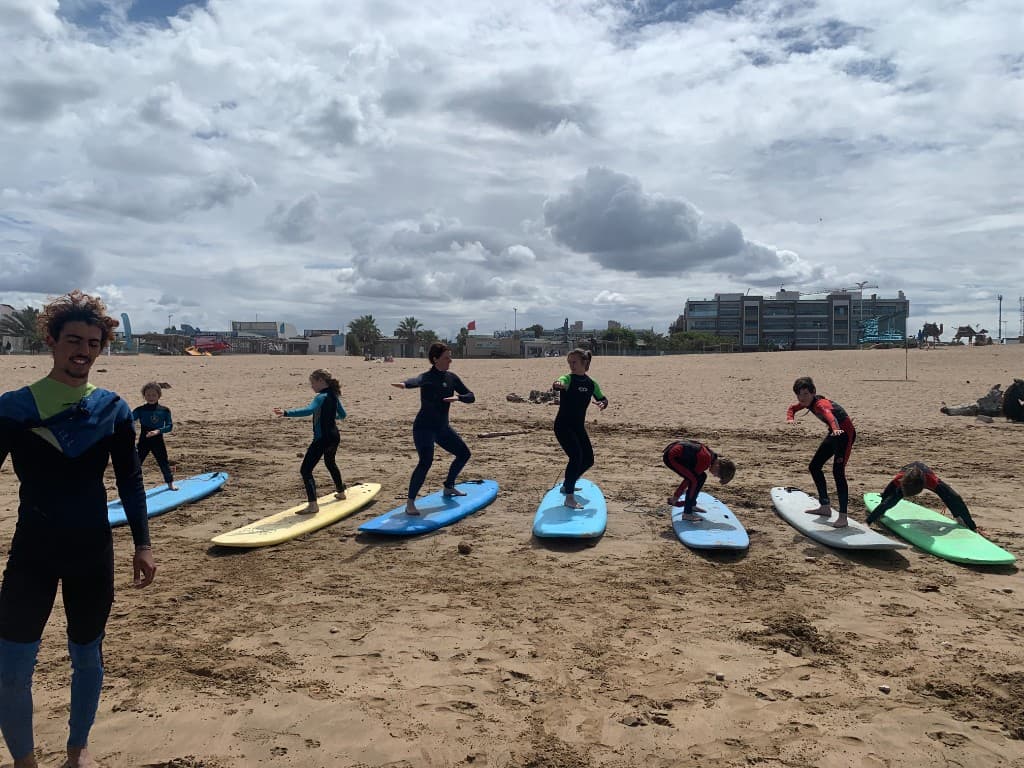 Group surf lesson on Essaouira beach — students on boards practising stance with an instructor